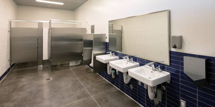 A modern, well-lit, and freshly sterilized commercial men's restroom, located somewhere in a medical facility.