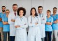 A group of doctors and nurses standing together. They all have their arms crossed and look happy to help.