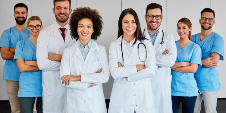 A group of doctors and nurses standing together. They all have their arms crossed and look happy to help.