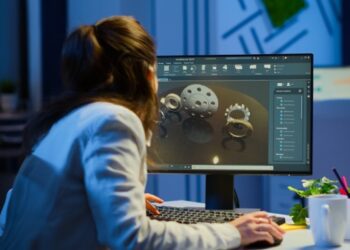 Female healthcare professional sitting at a desk inside an office using a computer displaying a render for equipment pieces.