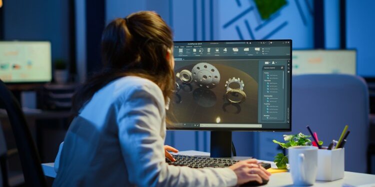 Female healthcare professional sitting at a desk inside an office using a computer displaying a render for equipment pieces.